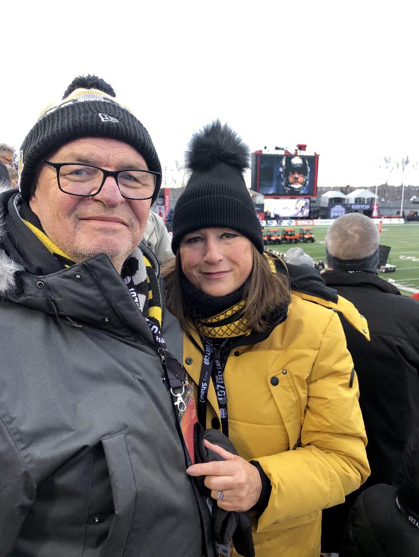 Rebecca and her husband. Bill Kelly, at the 2019 Grey Cup cheering for the Hamilton Tiger Cats as the Chairman of the Tiger Town Council..